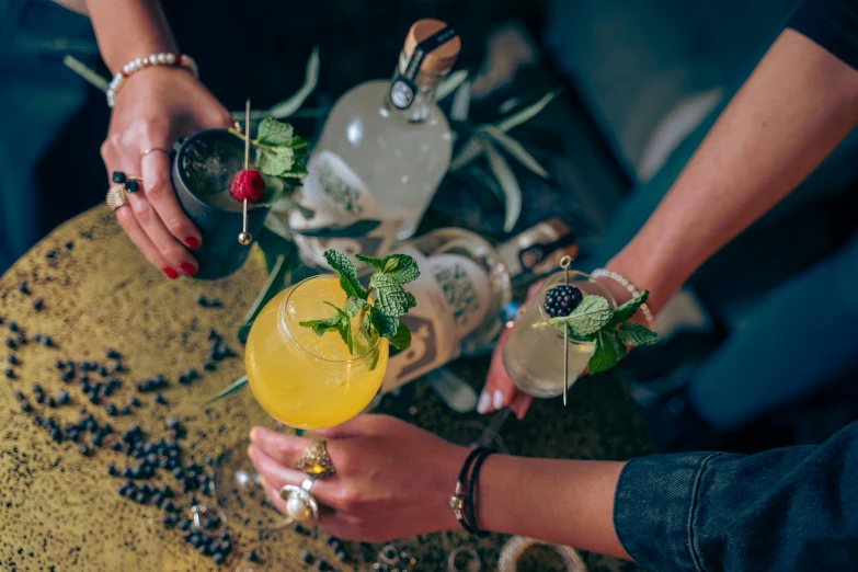 people hold their drinks together in front of the wine bottles