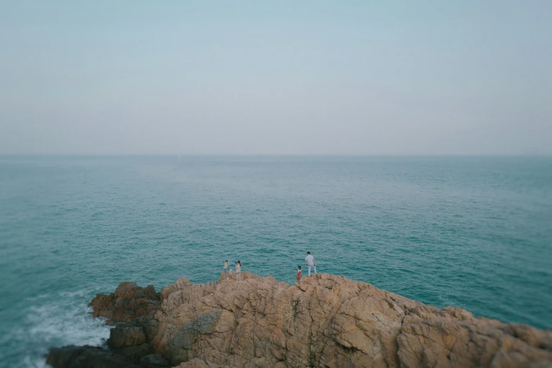 a couple people standing on the rocks by the ocean