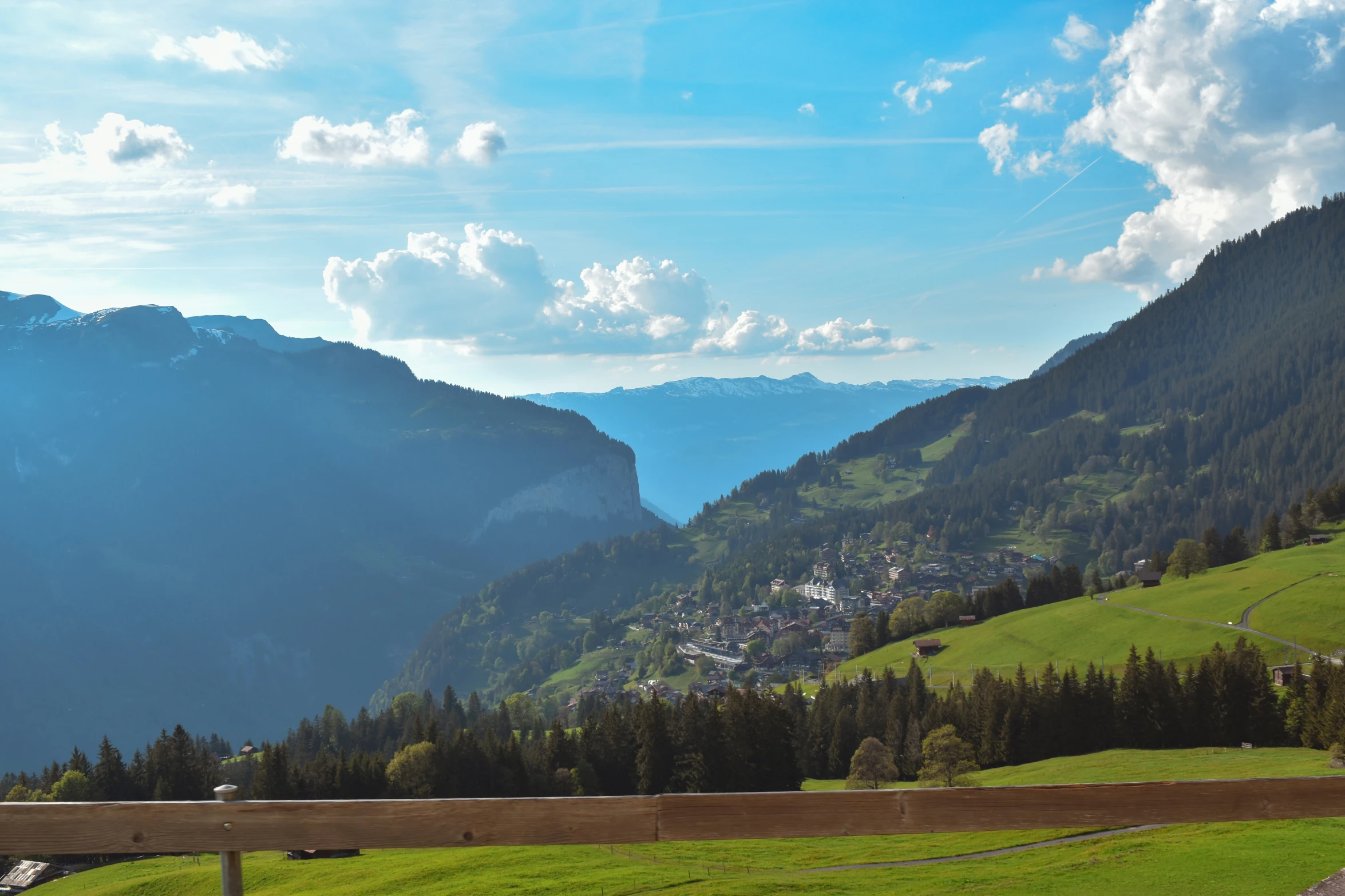 a mountain that has a lush green field next to it