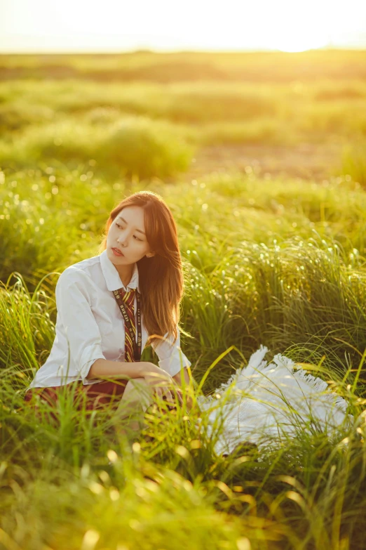 a woman in a dress shirt and tie sits in a field of grass