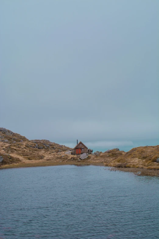 a small building is in the middle of a lake