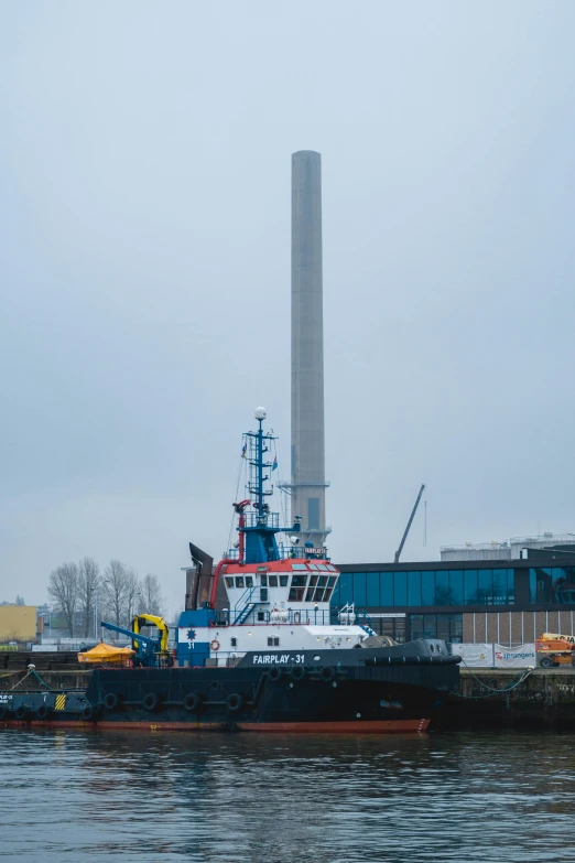 a ship is docked by the dock in front of a large power plant