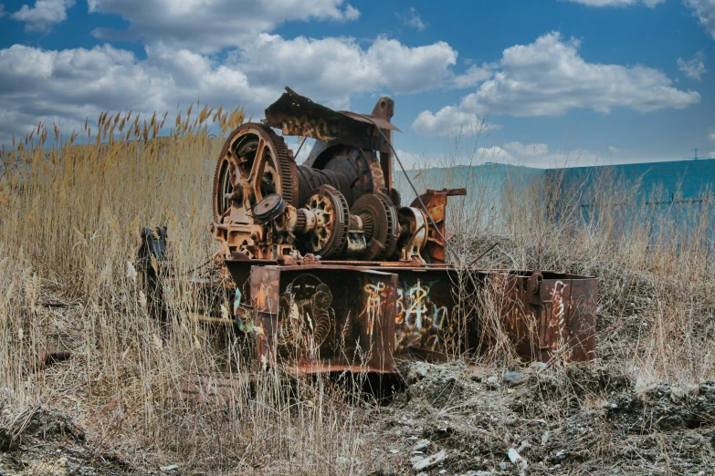 an old rusty cart is in the middle of tall grass