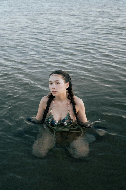 a woman is floating in a body of water with her long hair tied back