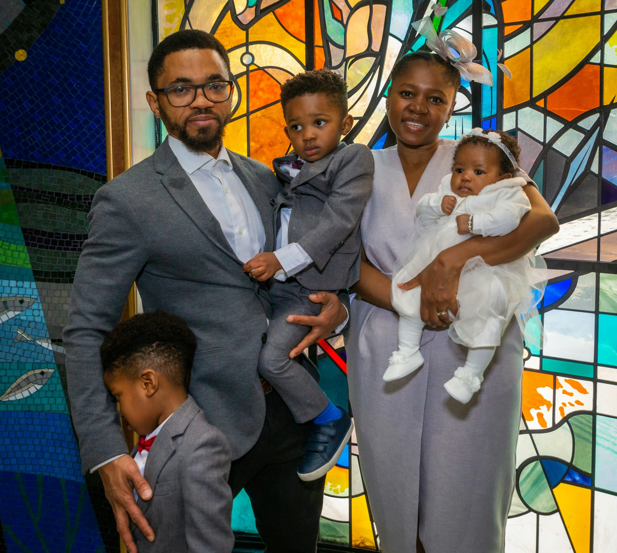 the family is posing in front of a stained glass window