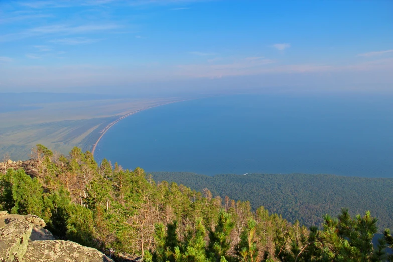 a person sits on the top of a large cliff overlooking trees