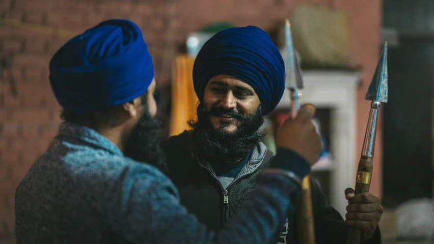 man with blue turban talking to another man