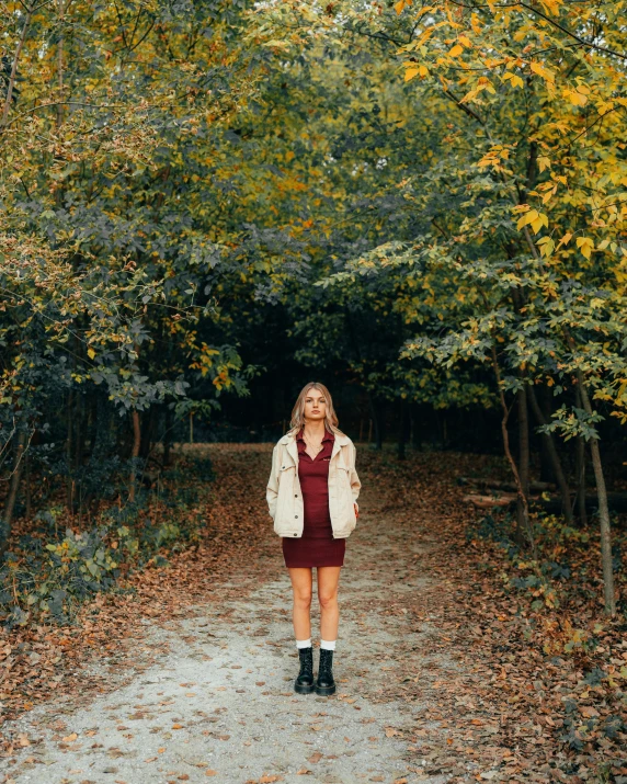 there is a woman standing on the road with the leaves on the trees