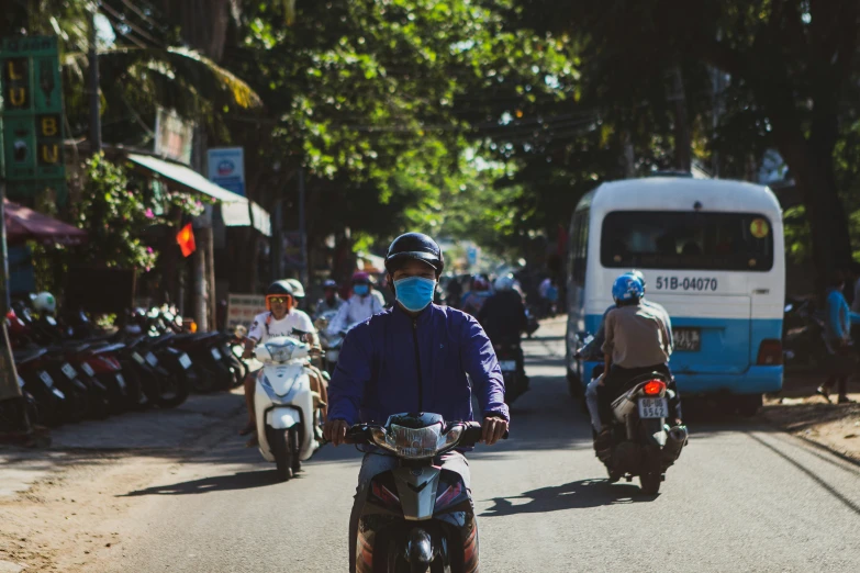 three people on scooters wearing a face mask