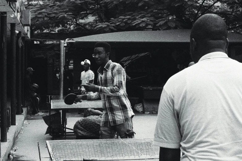 two men standing near each other outside in black and white