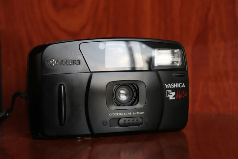 black camera with wooden back and red wood background