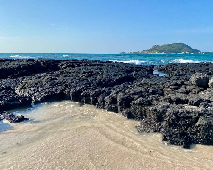 there is a rocky sea cliff with water lapping at the bottom