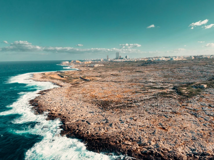 rocky shoreline on coastline line with city in distance