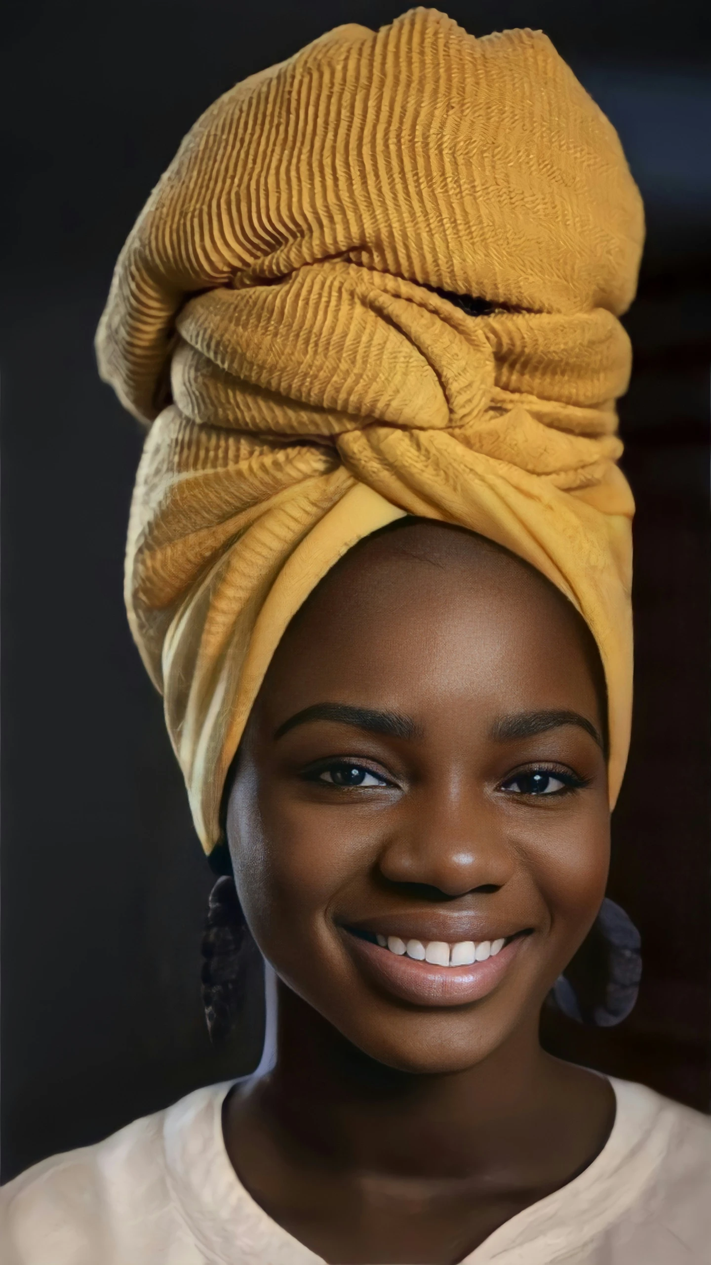 a woman wearing a turban smiles at the camera