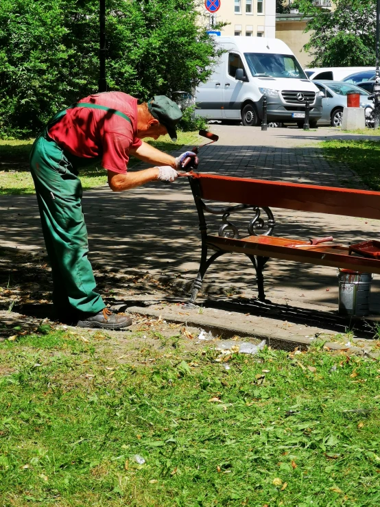 man bending down on a bench near grass