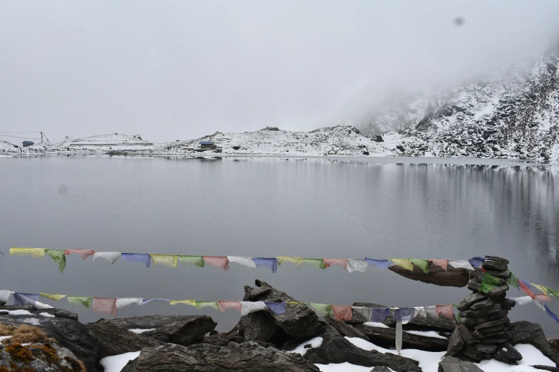 a couple of people are sitting on rocks near a lake