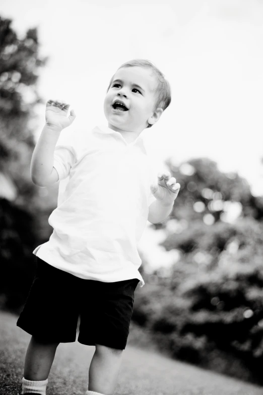 the small boy is walking in front of trees