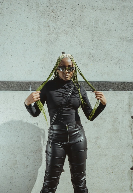 a woman in black leather and neon green hair standing