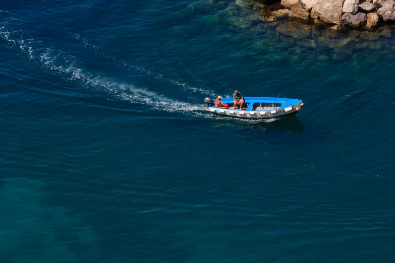 a boat in the water going by a rocky coast