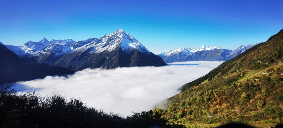 a big mountain surrounded by some clouds and trees