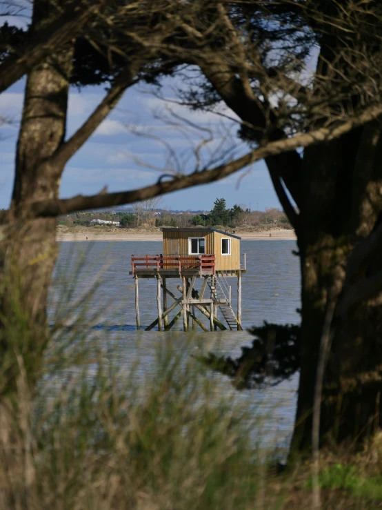 an outbuilding with a deck and chairs on top of it in the water