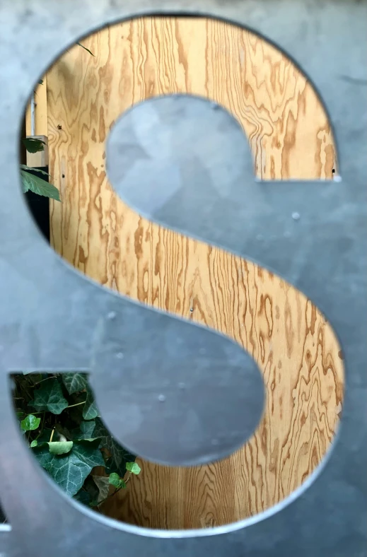 a wooden sign with a wooden number and plants in the background