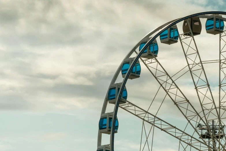 a ferris wheel sits in a field and cloudy skies