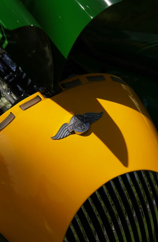 the front end of an old yellow car with a bird emblem on it