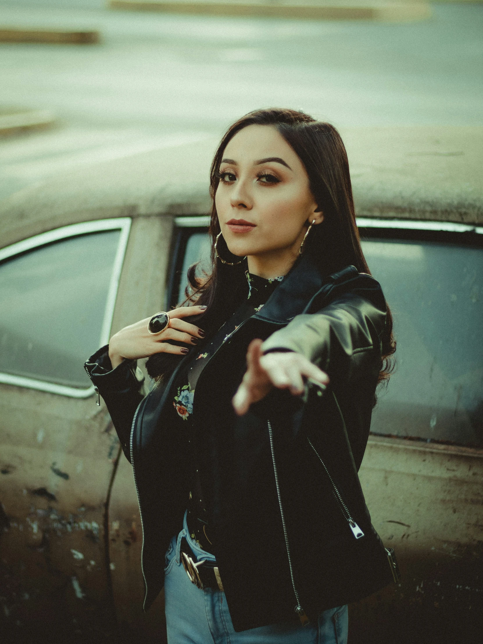 a woman standing outside of an old car with her hand on the door handle