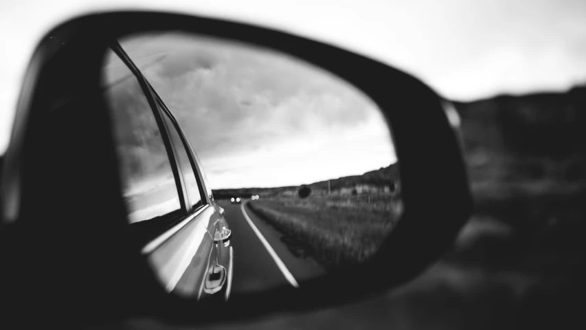 a rear view mirror reflecting a car driving on a highway