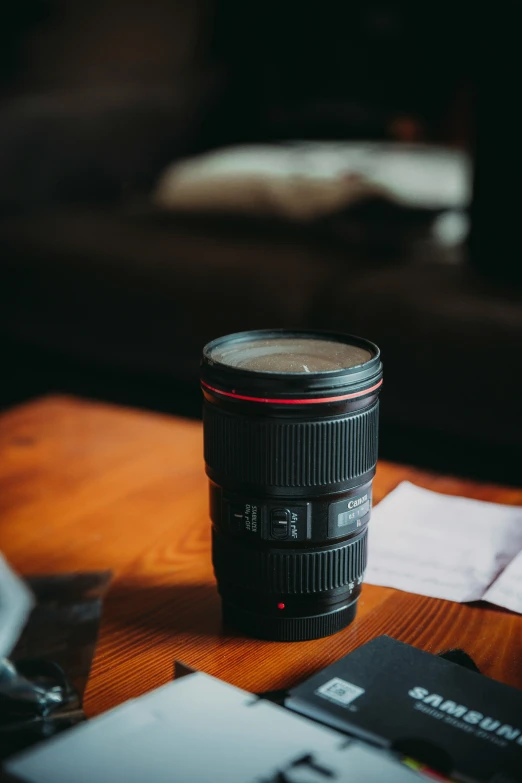 a camera lens sitting on top of a desk next to some paperwork