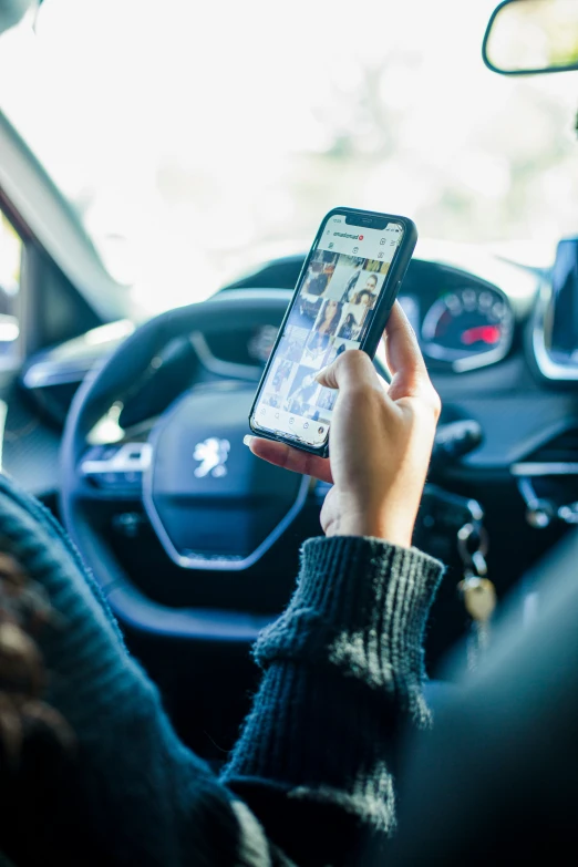 a person uses their cell phone while sitting in the drivers seat of a car