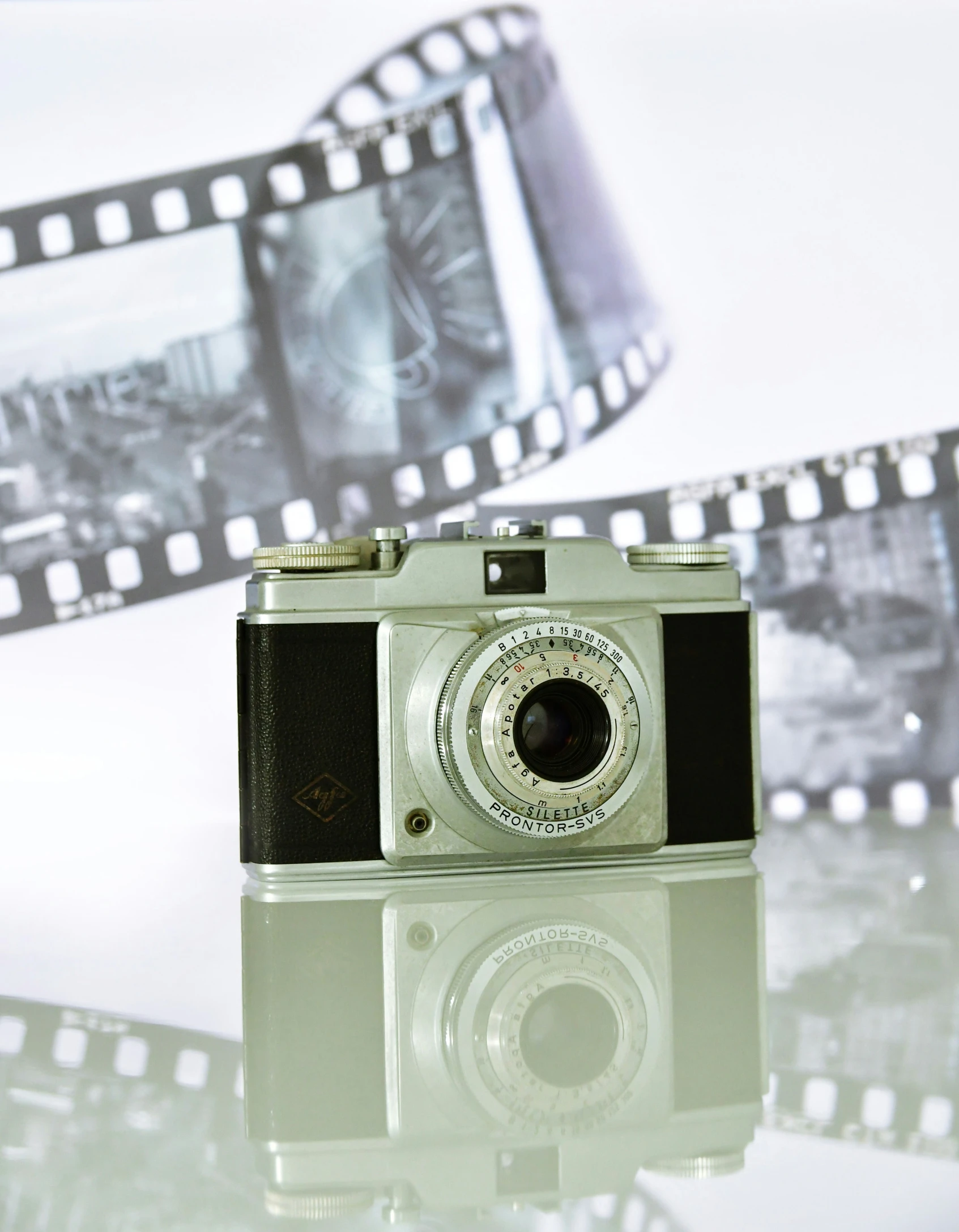 an old camera and film is reflected in a reflective surface