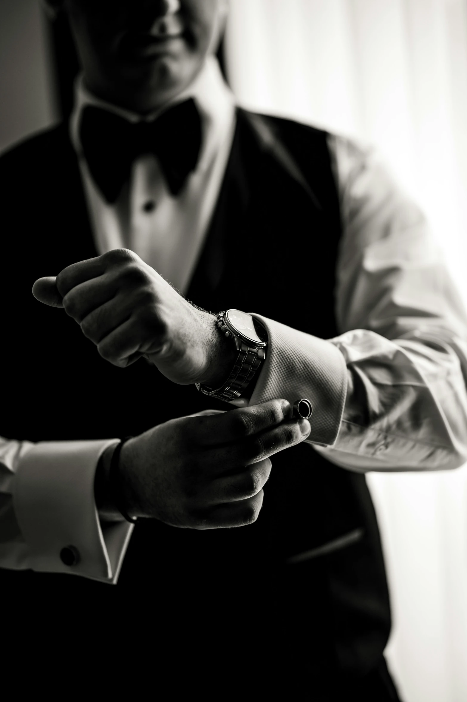 the man in the tuxedo is pointing to his watch