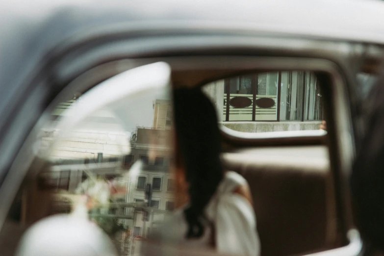 the car's rear view mirror is visible with a reflection of a person