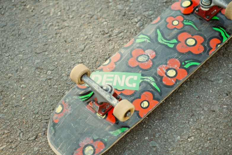 a skateboard with flowers painted on it is in the middle of cement