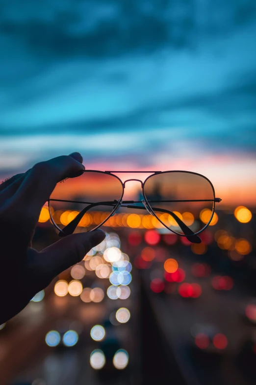 someone holding their glasses over the city skyline