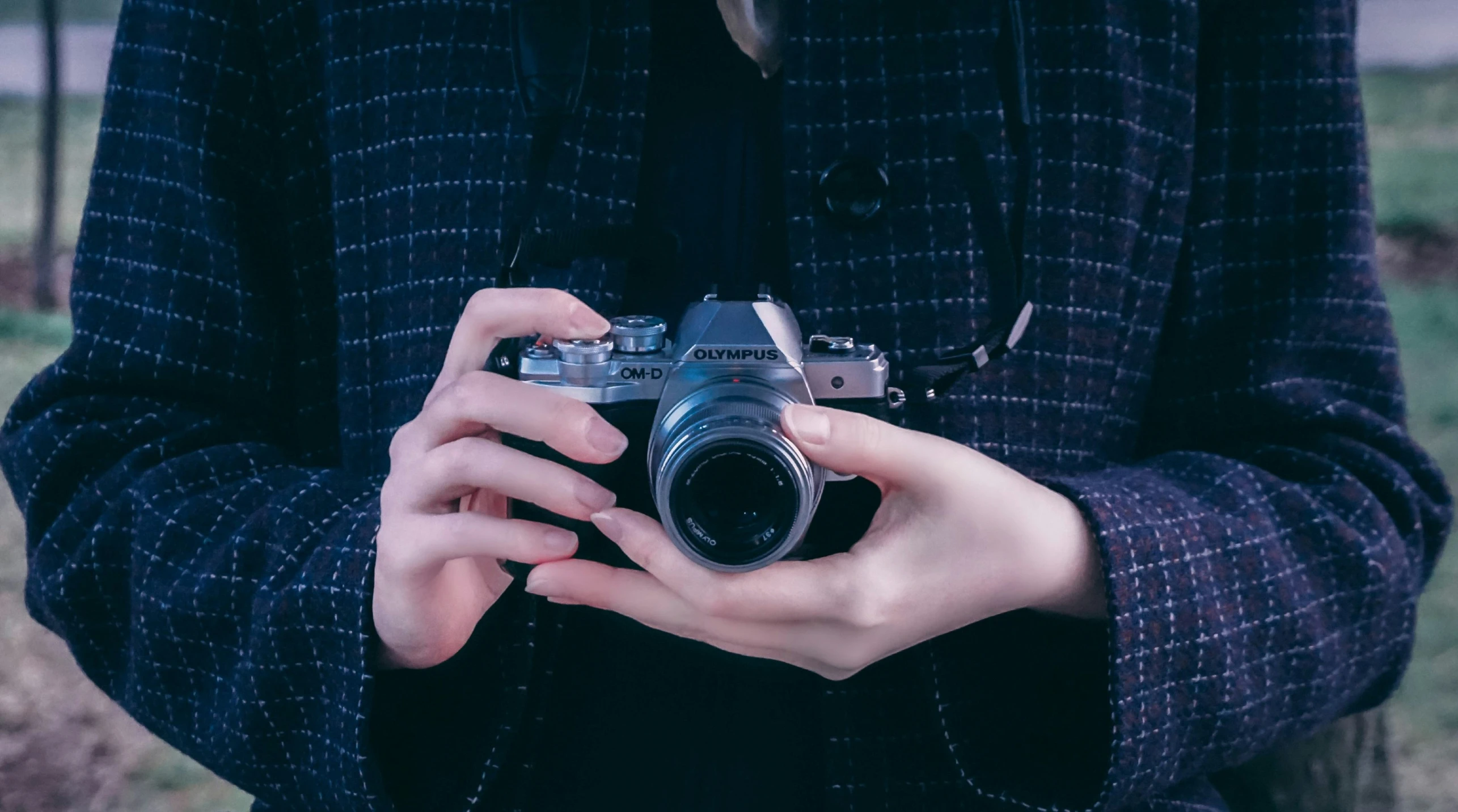 a person holds a camera while standing in a field