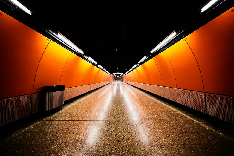 a walkway between two orange walls in a dark room