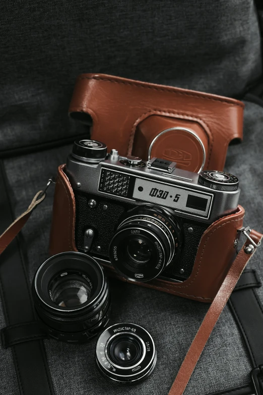 an old camera and lenses are sitting on a leather pouch