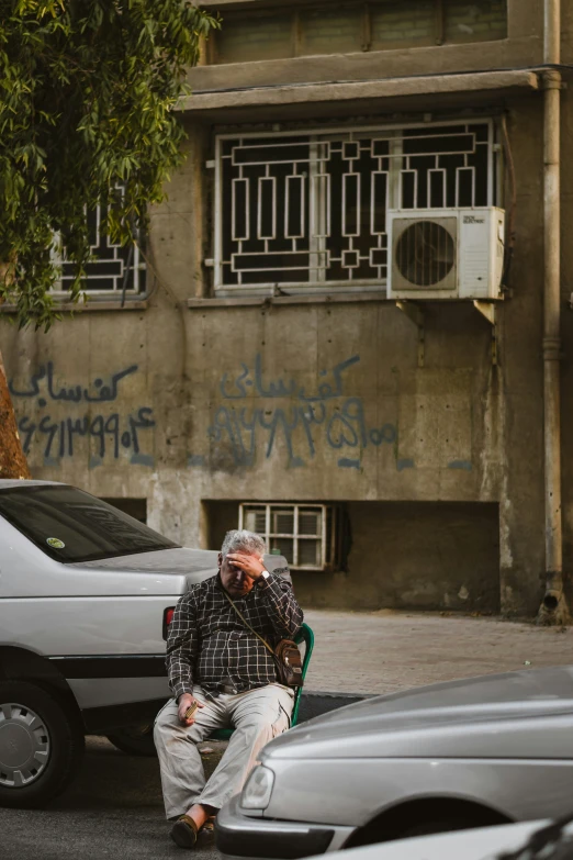 there is a man sitting on the street with a skateboard