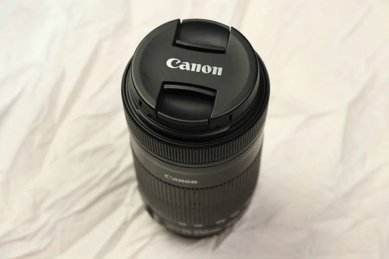 the top half of a canon lens on a bed