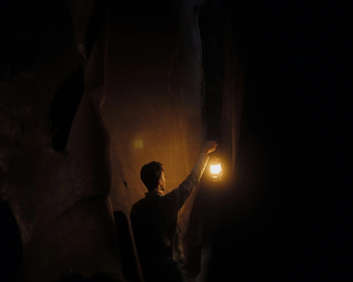 person holding lantern above dark alley in dark area