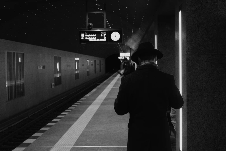 man standing near a train platform looking at the train