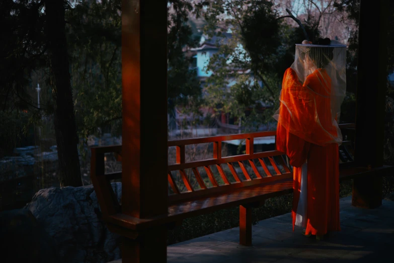 the woman in red dress is walking near a bench