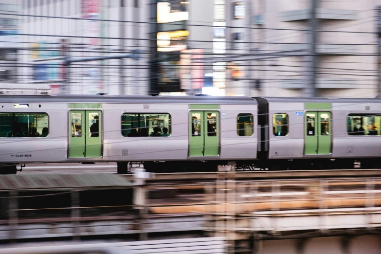a silver and green metro train with other people on the side of the track