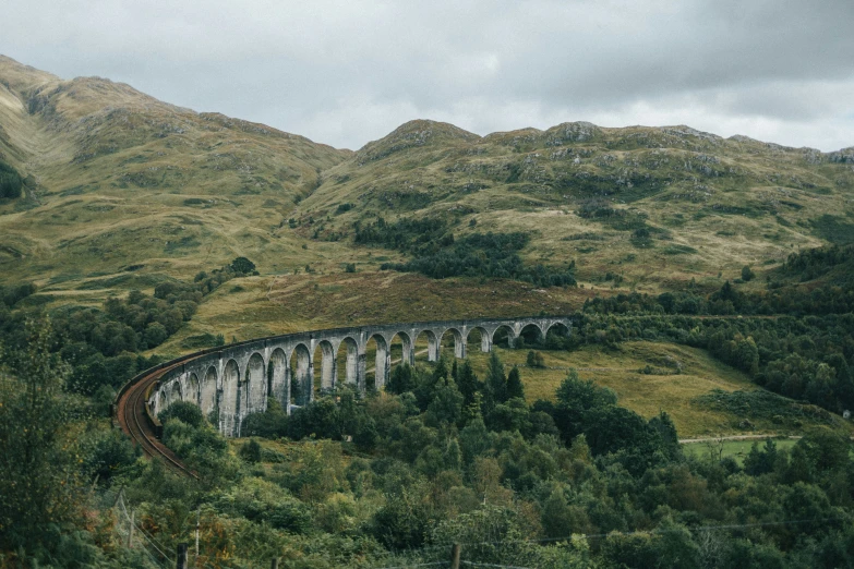 an old train traveling over a lush green mountain side