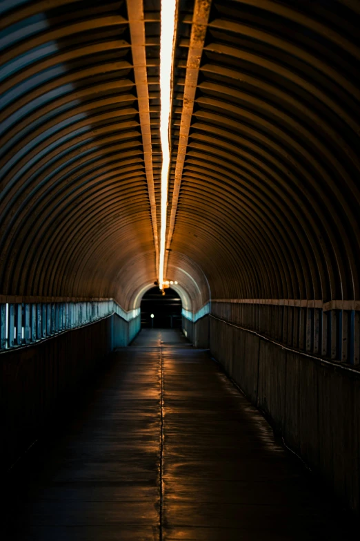 a lit walkway under a long, dark tunnel