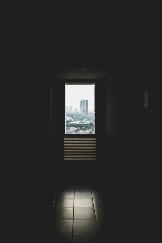 a window in a dark room with a tile floor and skyline seen through it