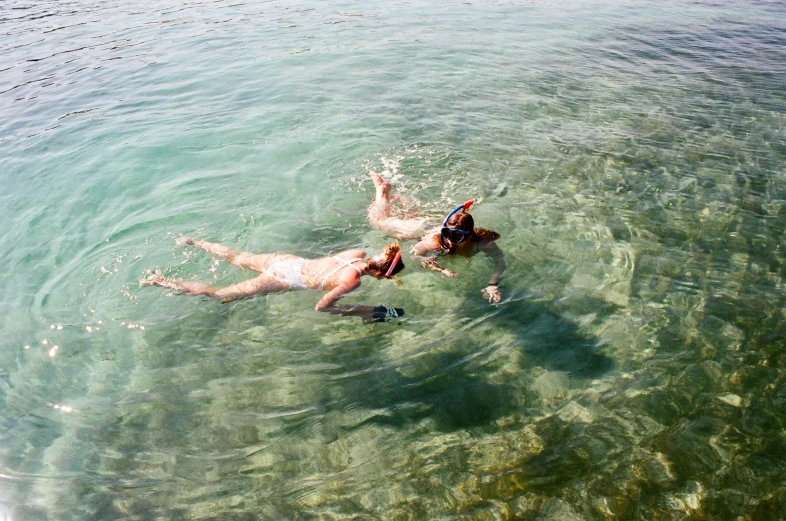 two people floating down in the water next to each other